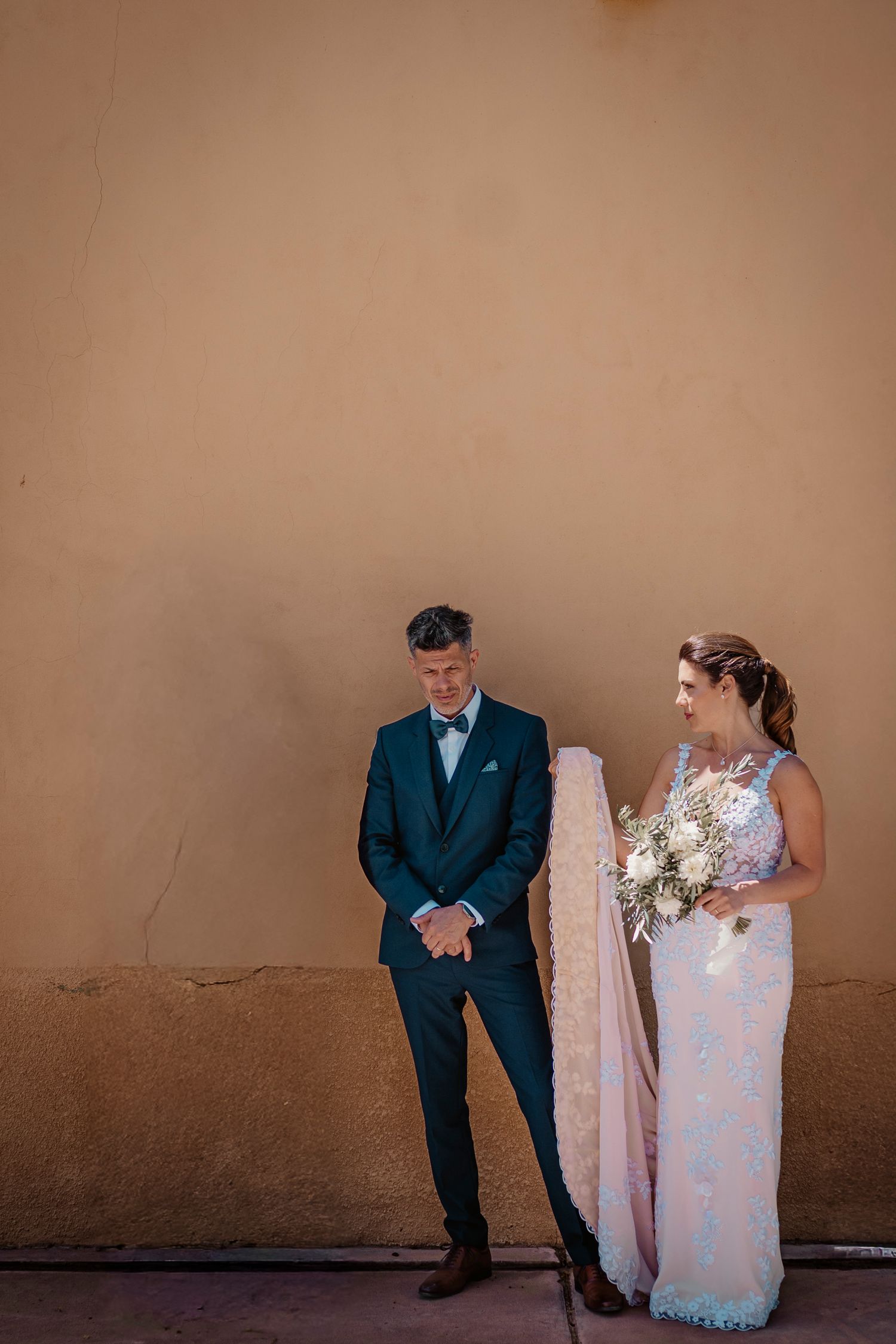 A creative wedding photo series showing playful poses between a couple against a neutral wall background.