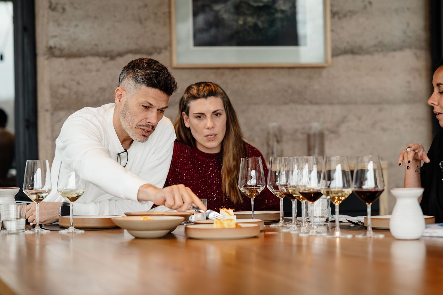 People seated at a long table in a restaurant drinking wine and enjoying a meal together.