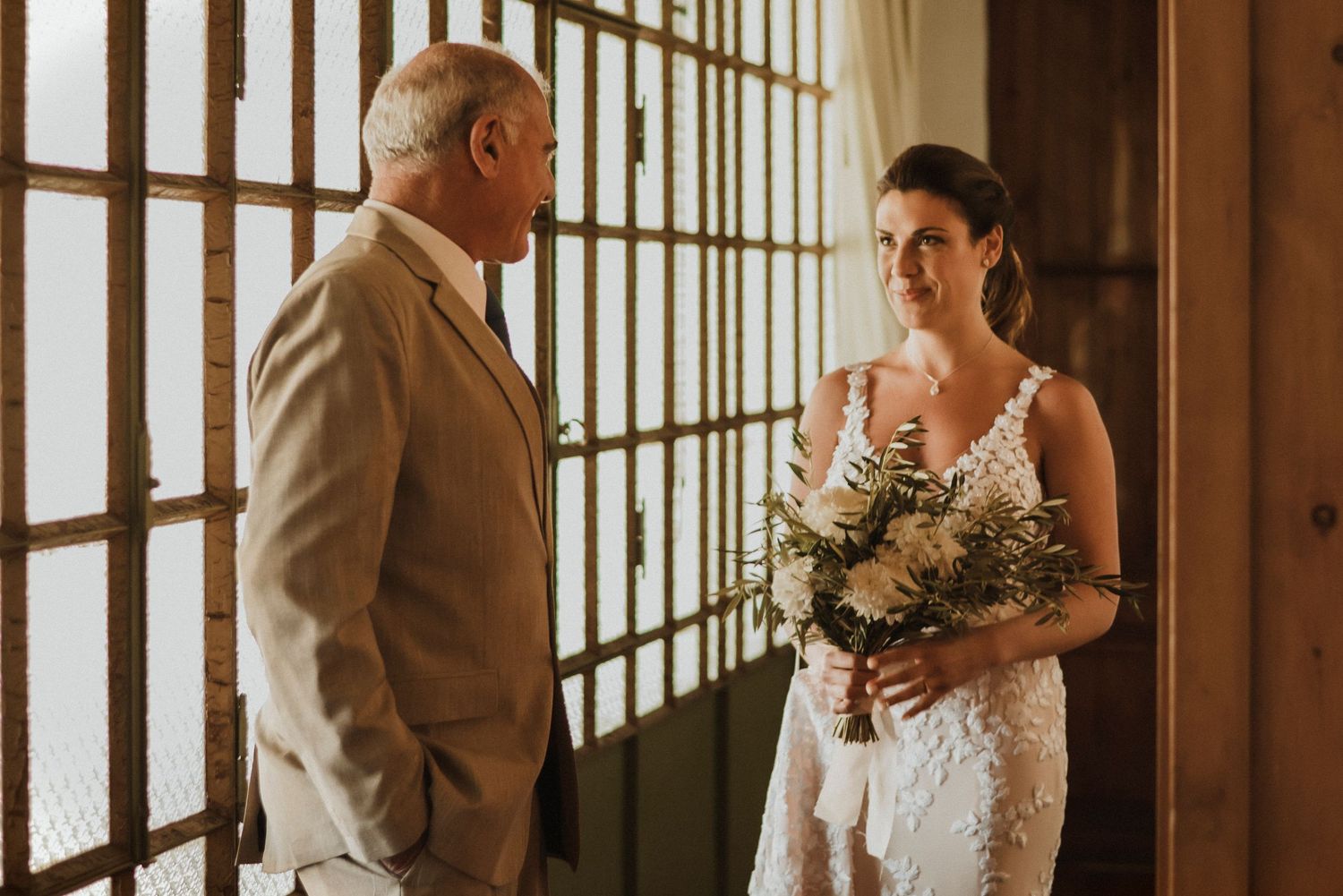 A bride and groom share an intimate moment in a rustic barn venue with natural light streaming through wooden beams.