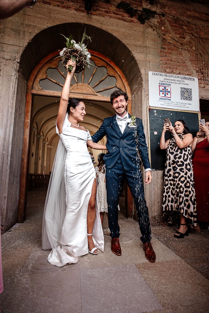 Wedding couple and guests dance joyfully in a rustic brick archway venue during reception celebration. wedding in mendoza