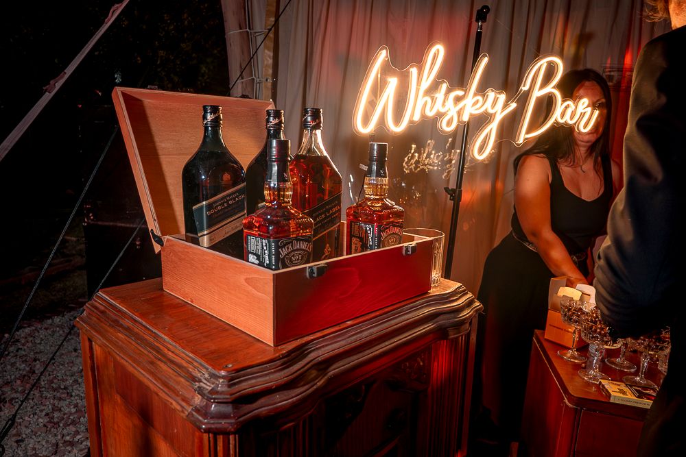Vintage whiskey bar with warm lighting displays bottles and glassware on wooden shelves in a cozy atmosphere.