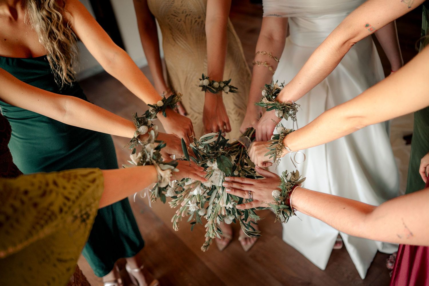Multiple hands work together to create decorative floral arrangements with greenery and flowers.