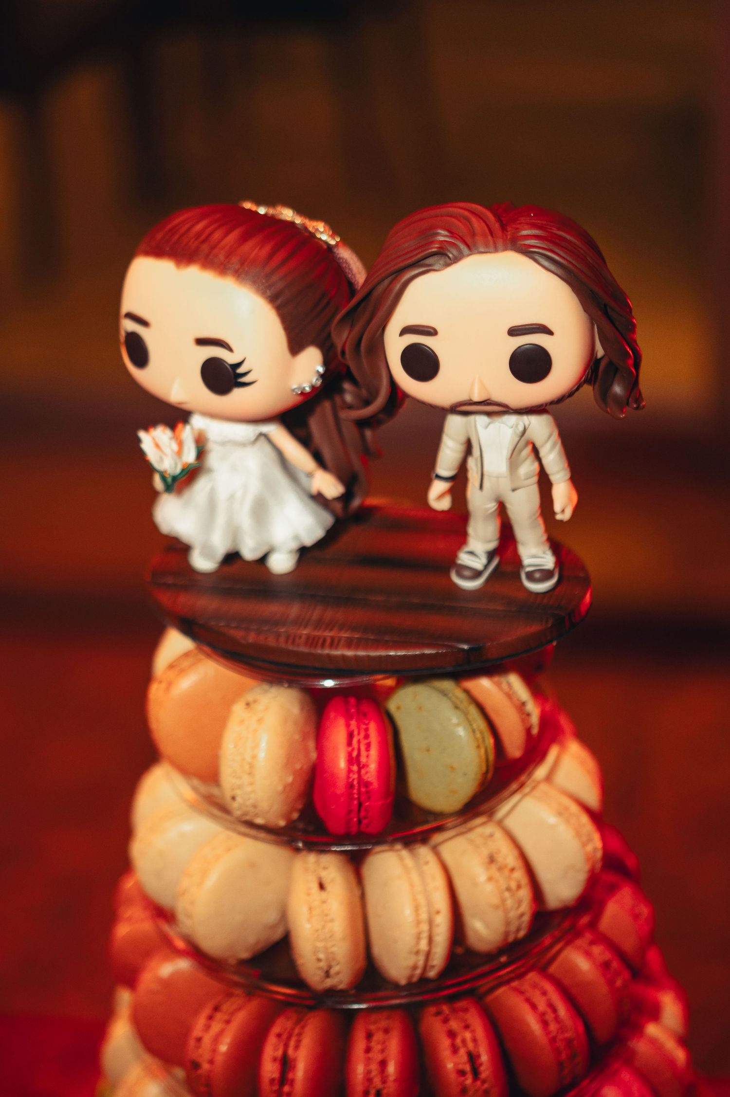 Funko Pop figures displayed alongside colorful French macarons on a dark wooden surface with dramatic lighting.
