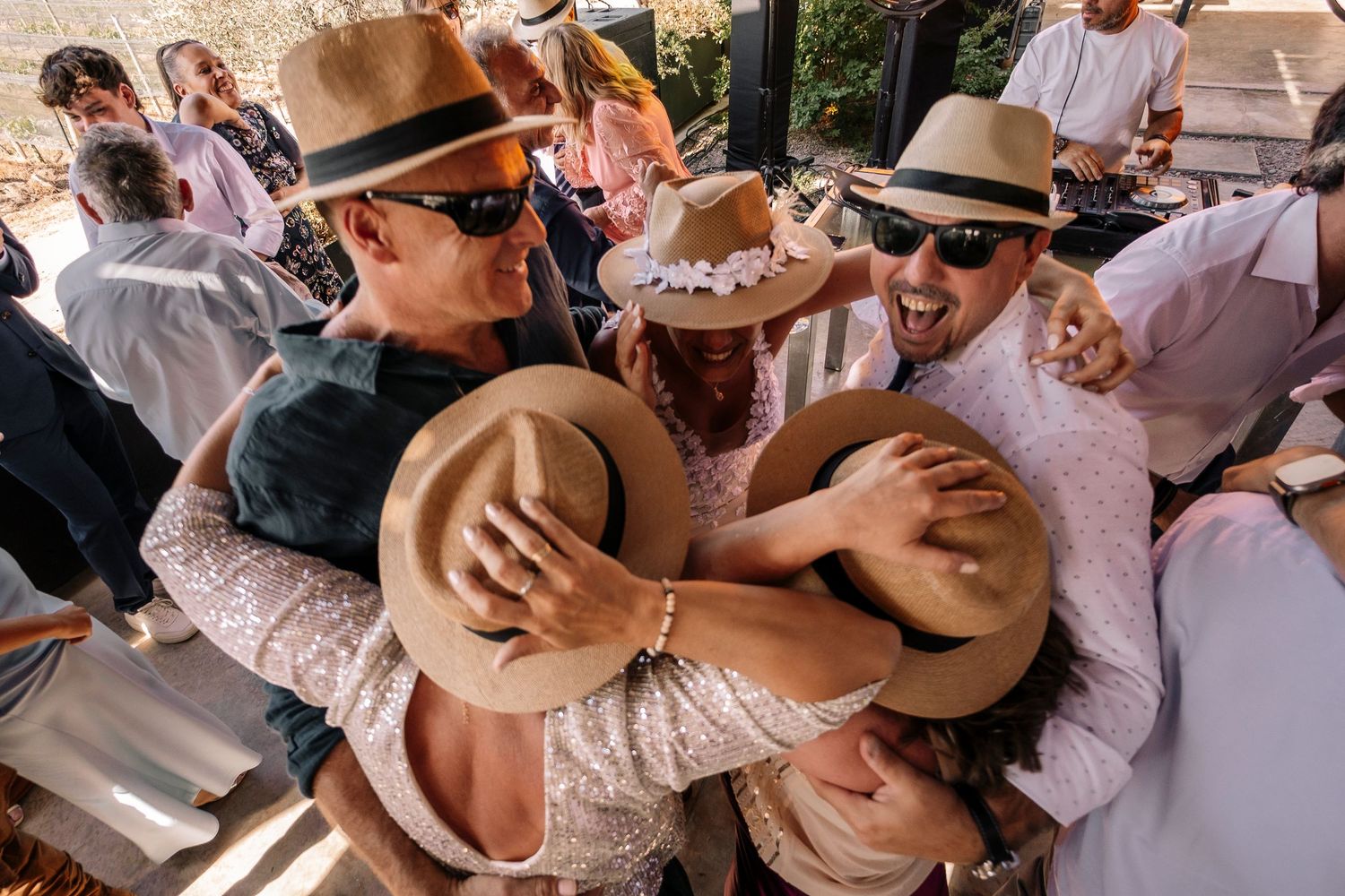 A romantic outdoor wedding celebration with couples dancing and embracing while wearing cowboy hats.