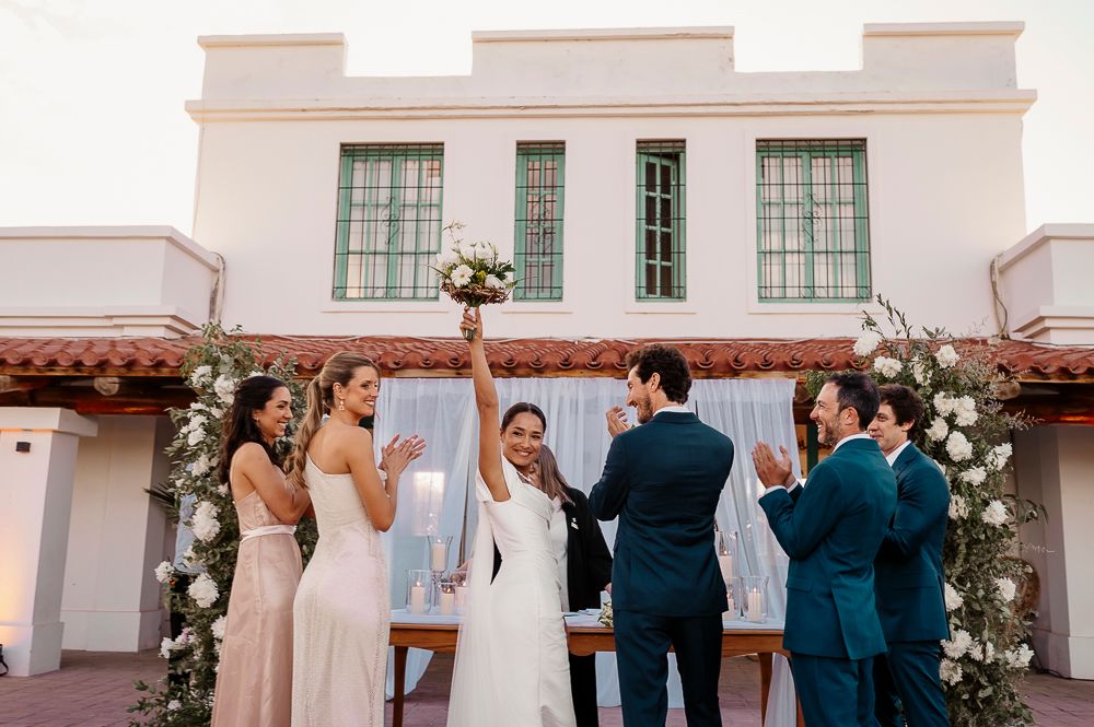 Wedding guests gather for a celebration in front of a white Spanish-style building with elegant floral arrangements. wedding in mendoza