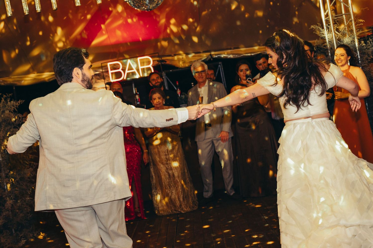 Couple performs their first dance at a wedding reception with sparklers and guests creating a magical atmosphere.