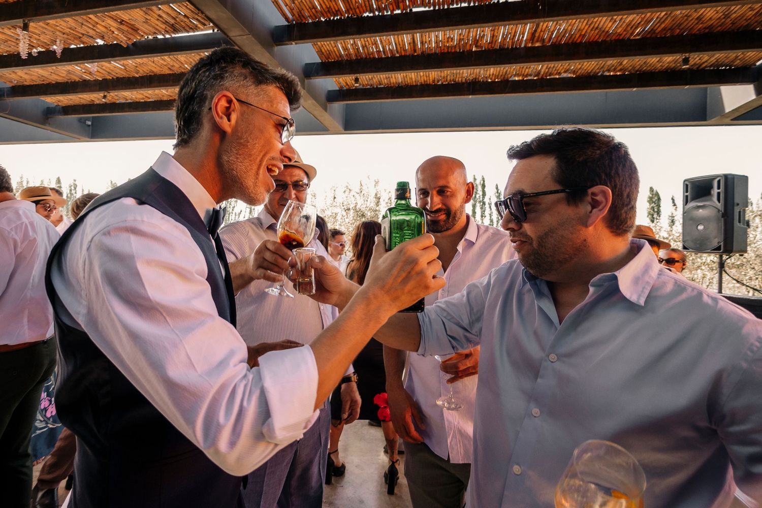 People gathered under a rustic wooden roof during what appears to be a social celebration or event.