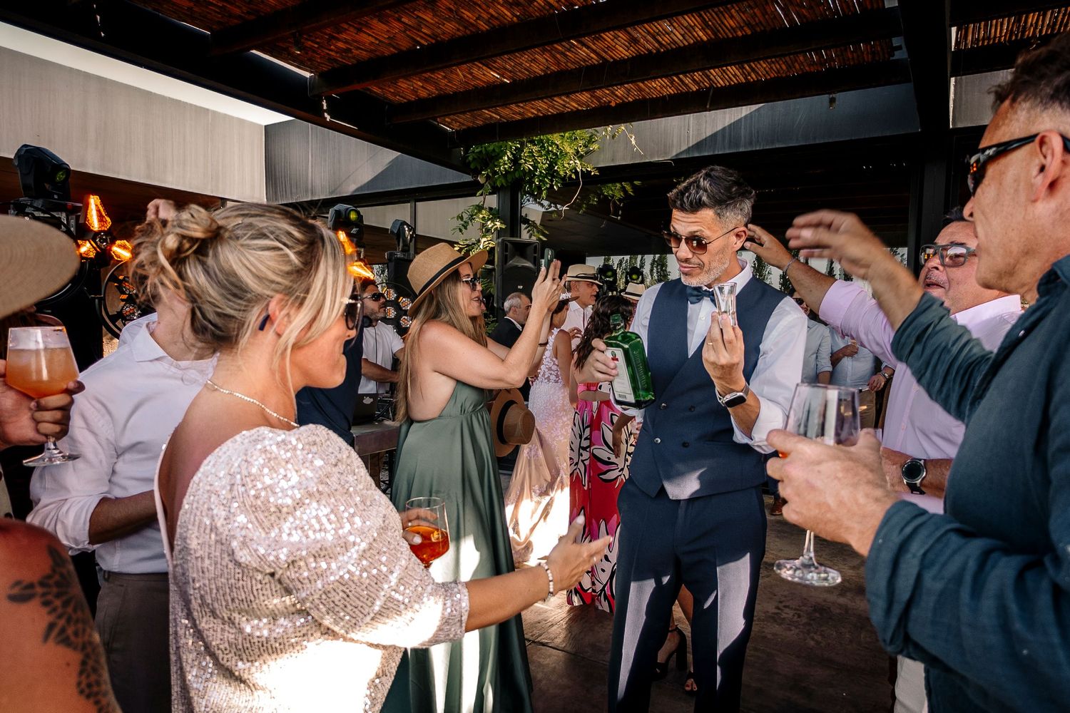 Wedding guests celebrate and raise their glasses during a lively reception under wooden beams.