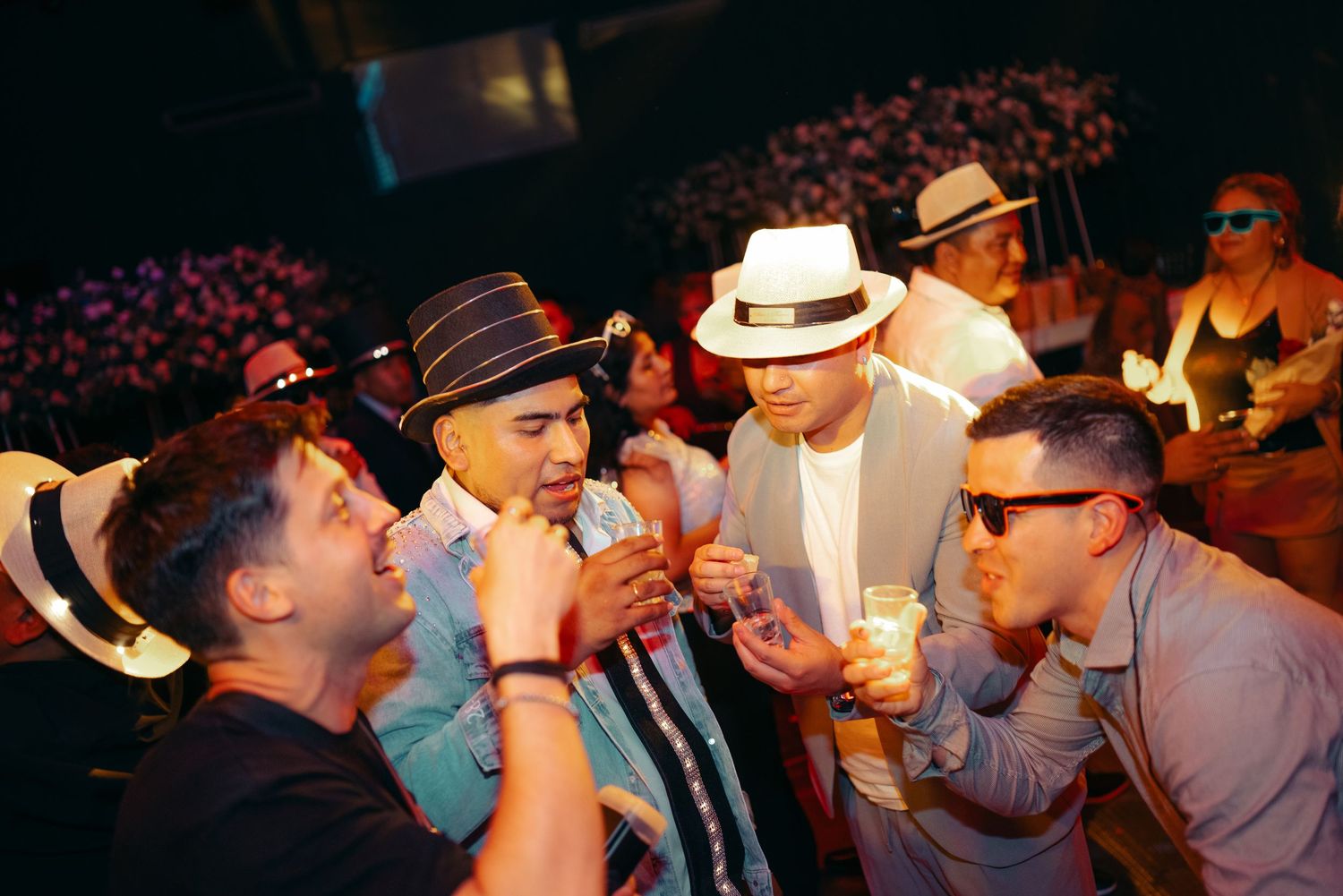 Group of people dressed in cowboy hats drinking beer and socializing at a western-style event.