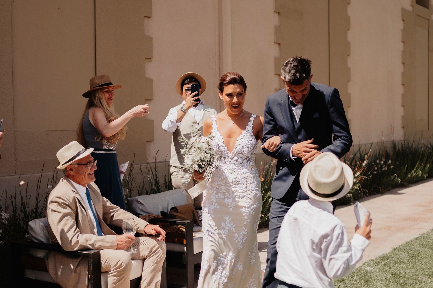 A group of people in white clothing and hats perform an energetic dance routine together outdoors.