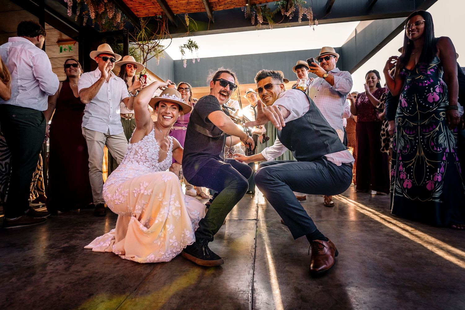 Wedding guests dance and celebrate on a rustic wooden dance floor during a reception party.
