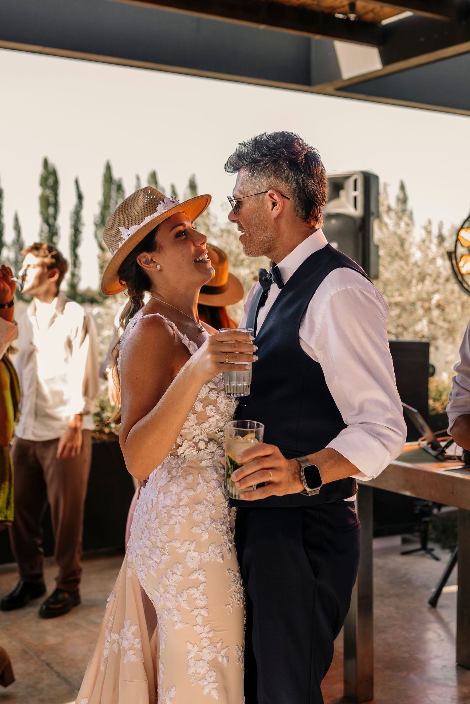 A joyful couple shares a candid moment during their wedding reception, with the bride in a lace gown and groom in a vest.