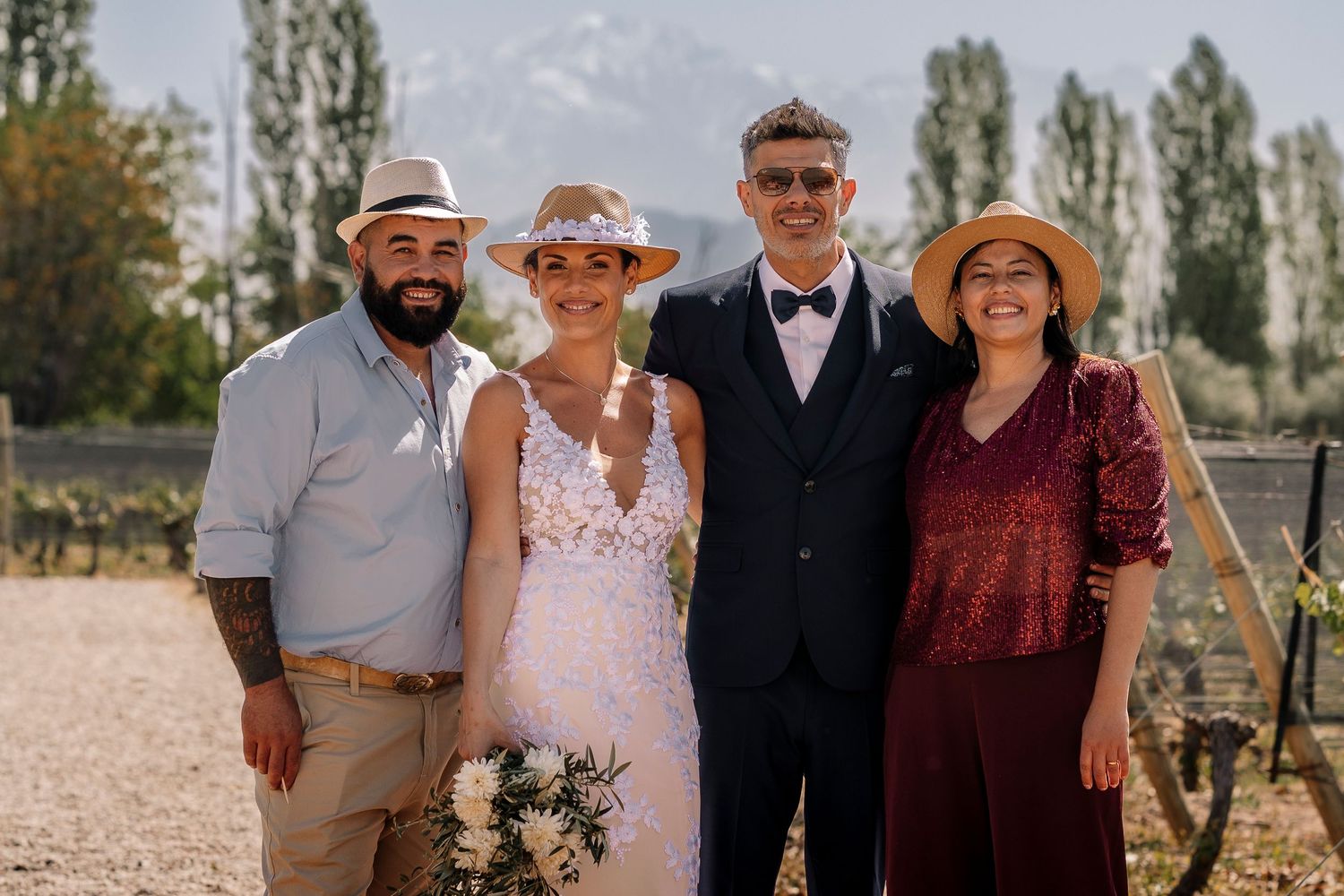 A group of people pose together outdoors on a sunny day wearing casual and formal attire for a family gathering.