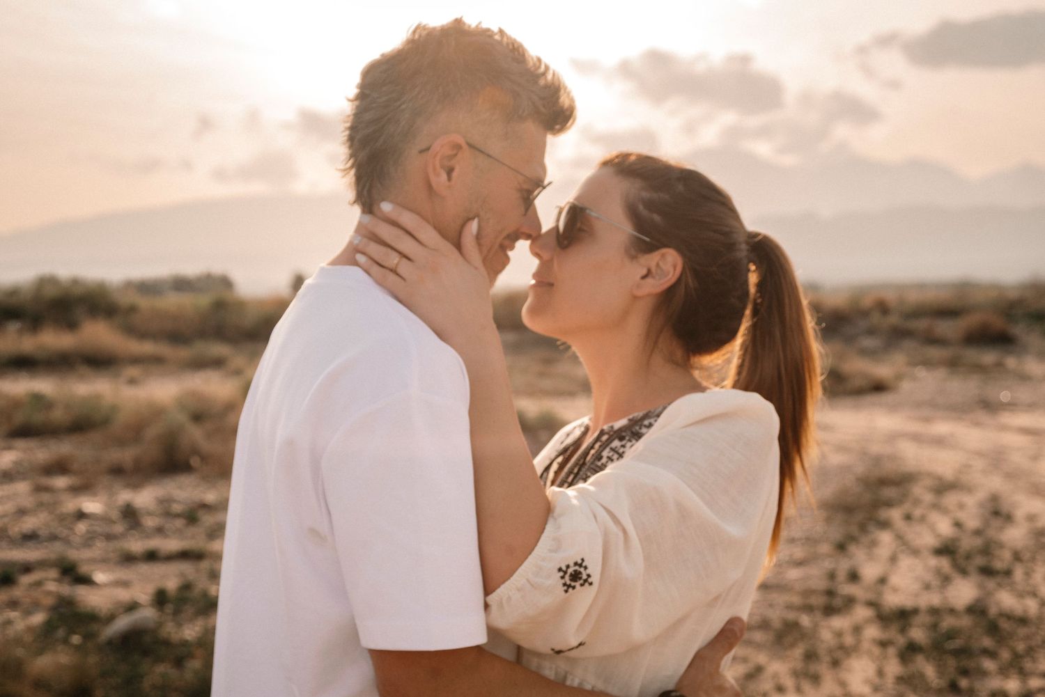 Romantic couple sharing intimate moments during golden hour on a scenic beach.