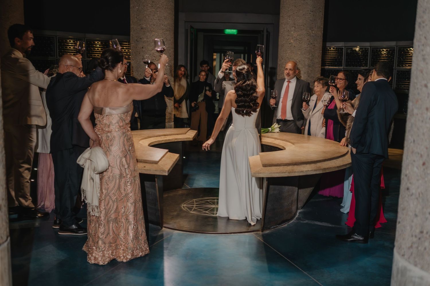 Elegant wedding reception with bride in white gown and guests celebrating in a grand venue with blue floors.