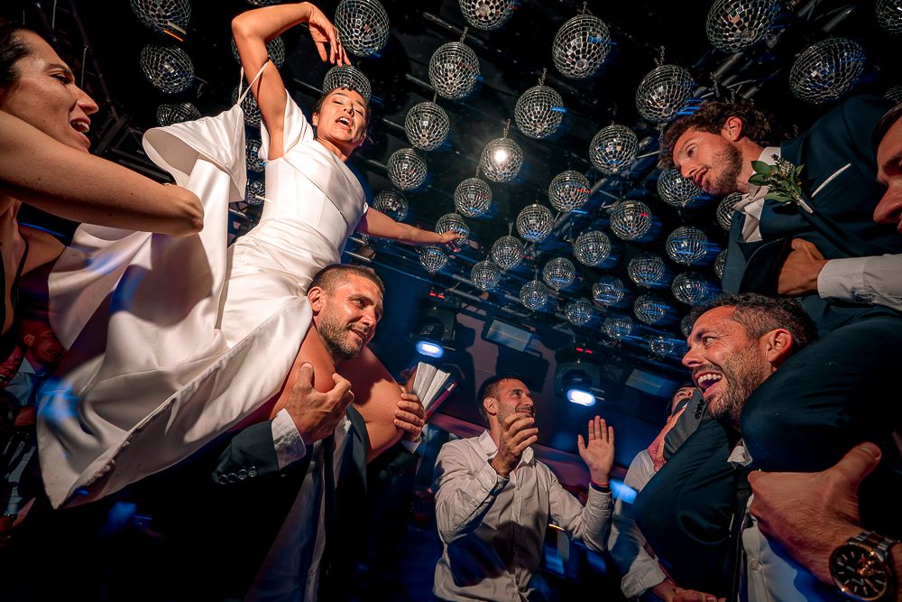 Energetic crowd of people dancing and jumping at a nightclub with blue lighting in the background. wedding in mendoza