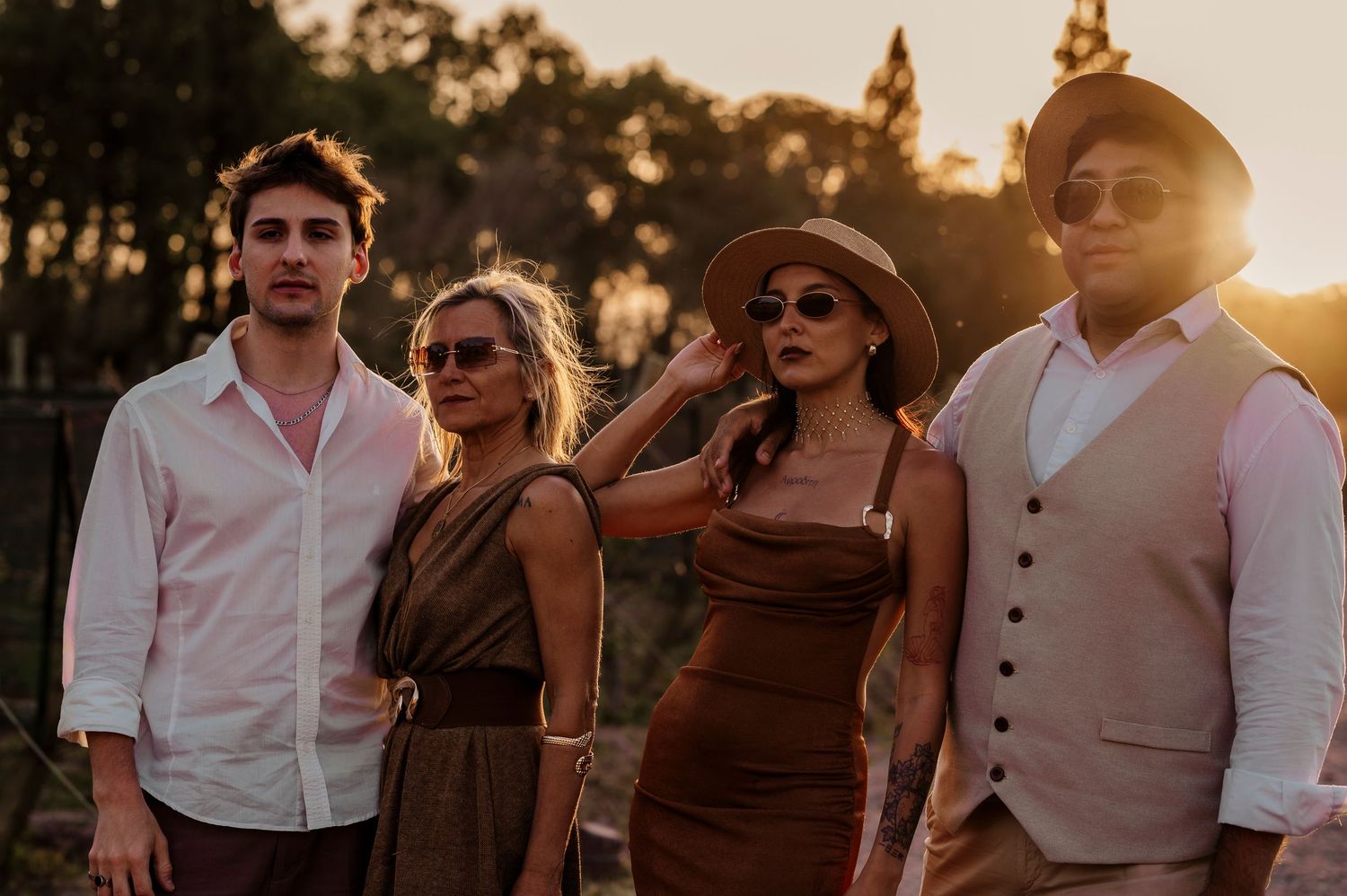 A group of people in formal attire laughing and enjoying themselves outdoors during golden hour sunset.