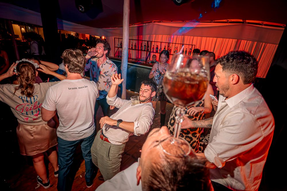 Party-goers dance and celebrate in a red-lit venue during a lively nighttime celebration. wedding in mendoza