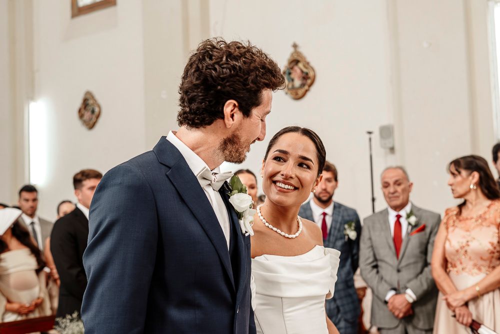 Joyful couple shares a candid laughing moment during their wedding ceremony while guests look on in the background. wedding in mendoza