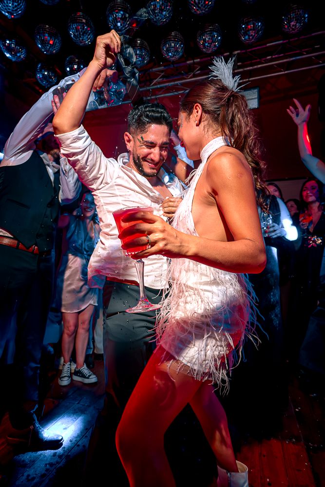A couple dances energetically at a nightclub with blue lighting and festive atmosphere. wedding in mendoza