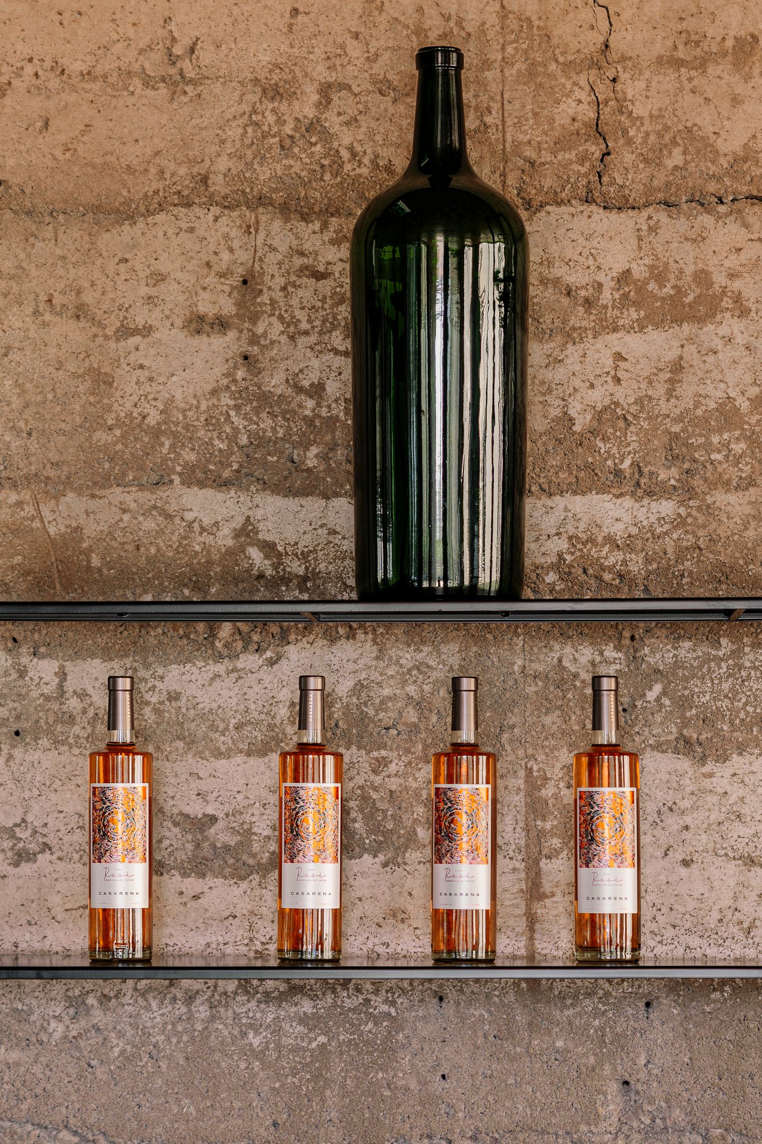 Amber glass bottles arranged in a row on rustic wooden shelves against a textured concrete wall.