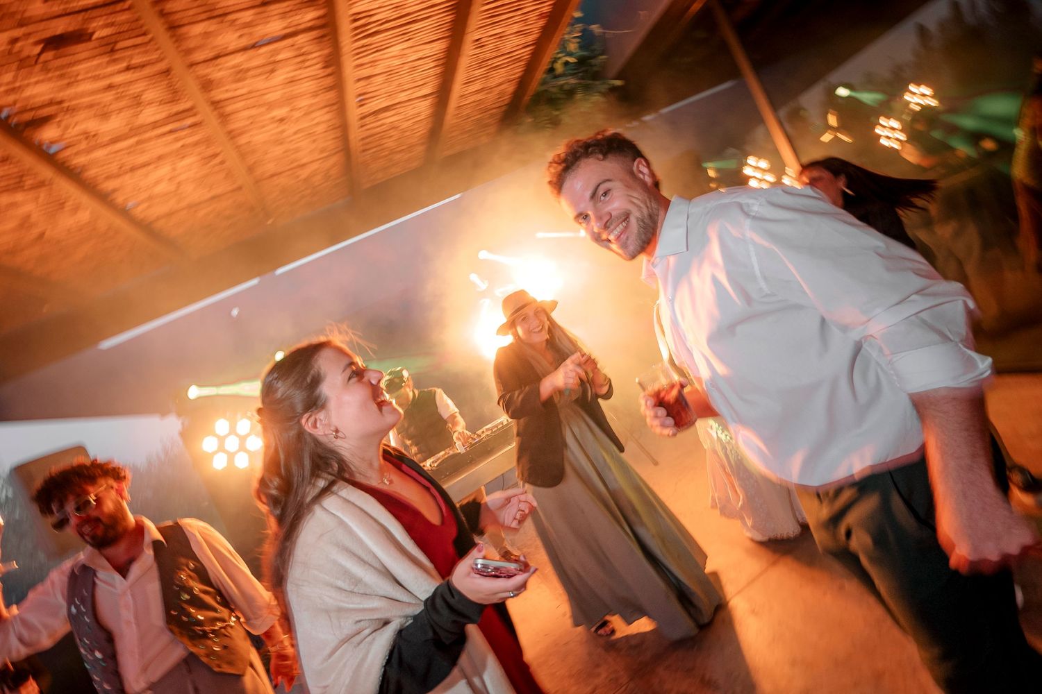 People dancing and celebrating at a wedding reception with warm lighting and dynamic movement on the dance floor.