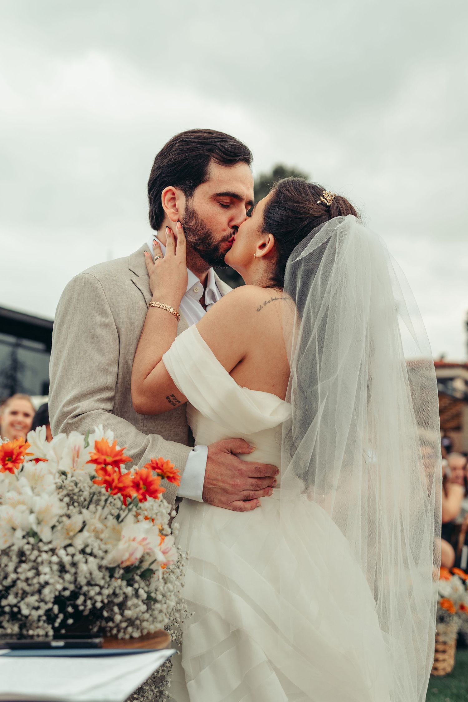 A romantic wedding kiss sequence showing the couple embracing in multiple candid moments with orange flowers in the background.