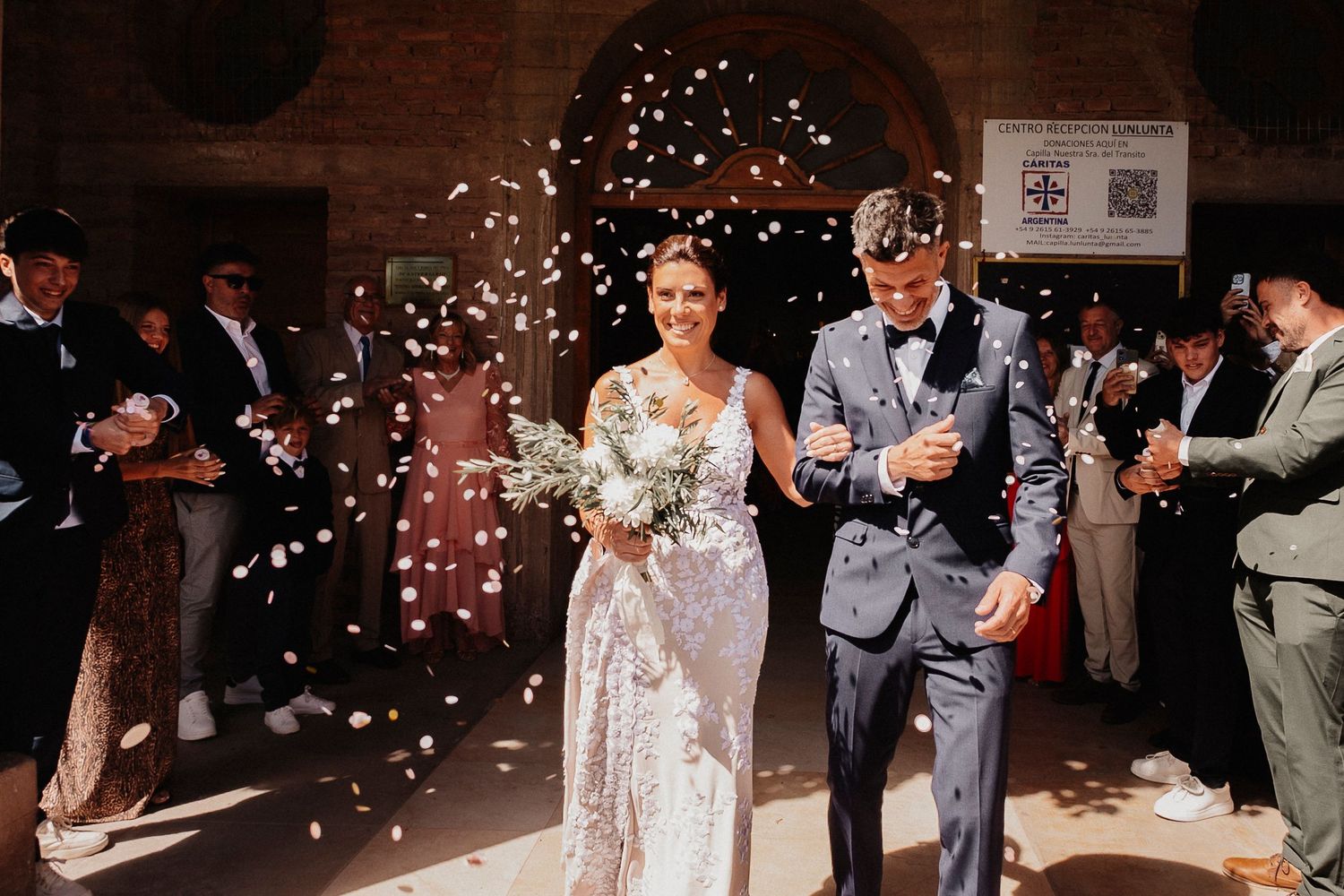 Wedding guests toss flower petals at newlyweds during their joyful exit celebration at an evening reception.