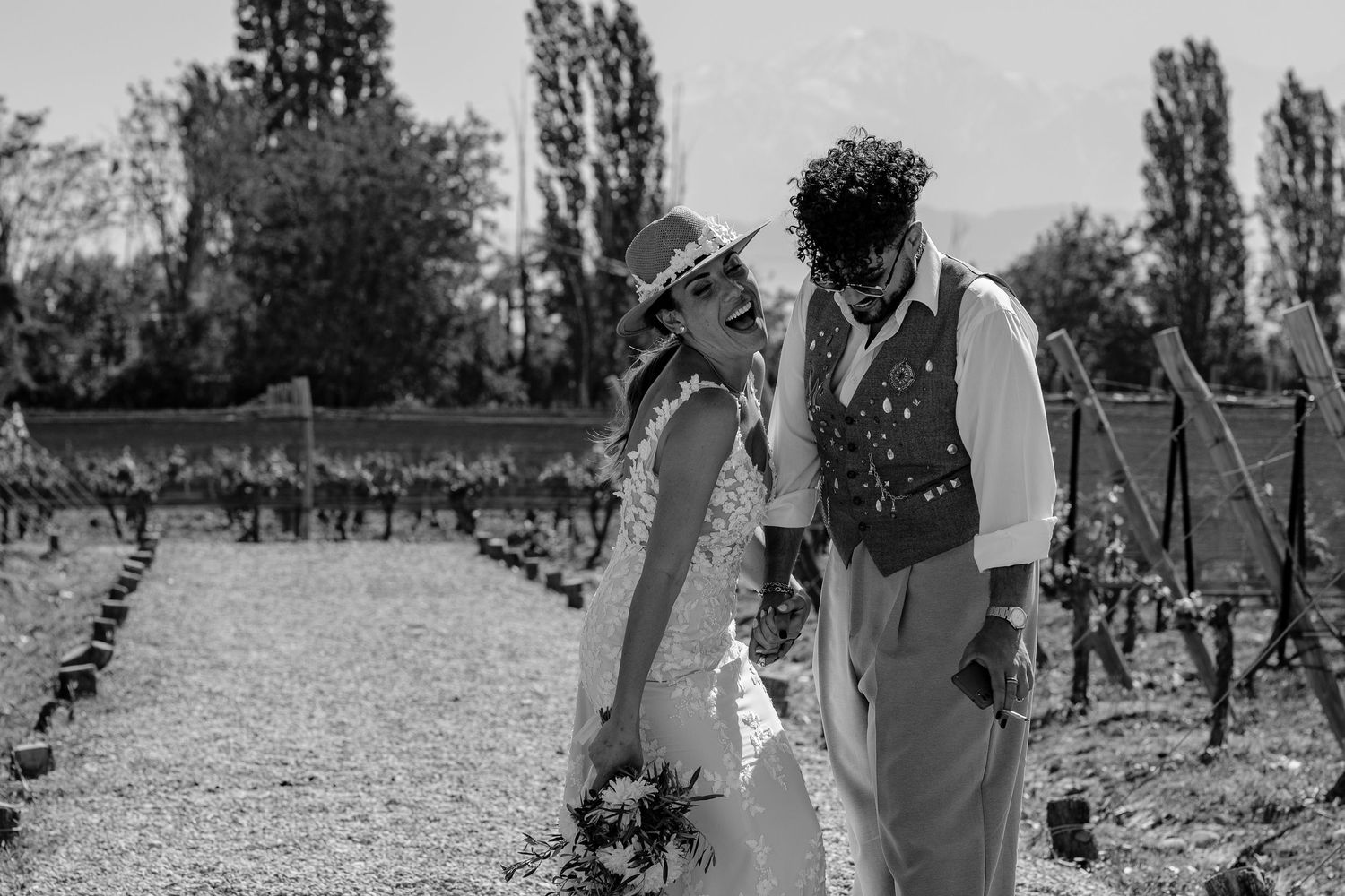 A couple shares a joyful moment together in a sunny vineyard setting during a romantic photoshoot.