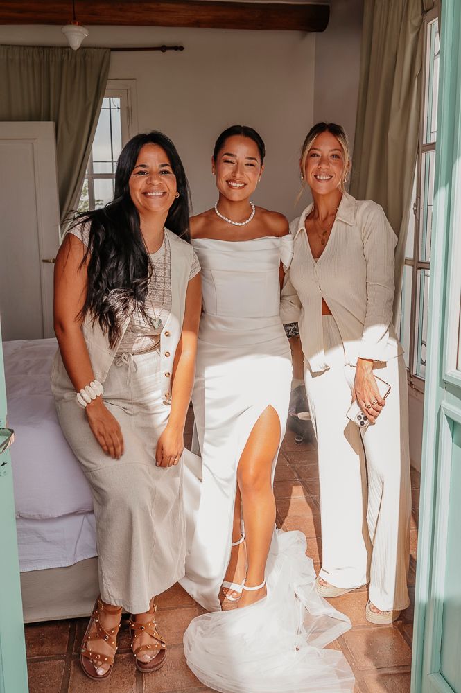 A group wearing white dresses and outfits poses together in a bright interior space with wooden beams. wedding in mendoza
