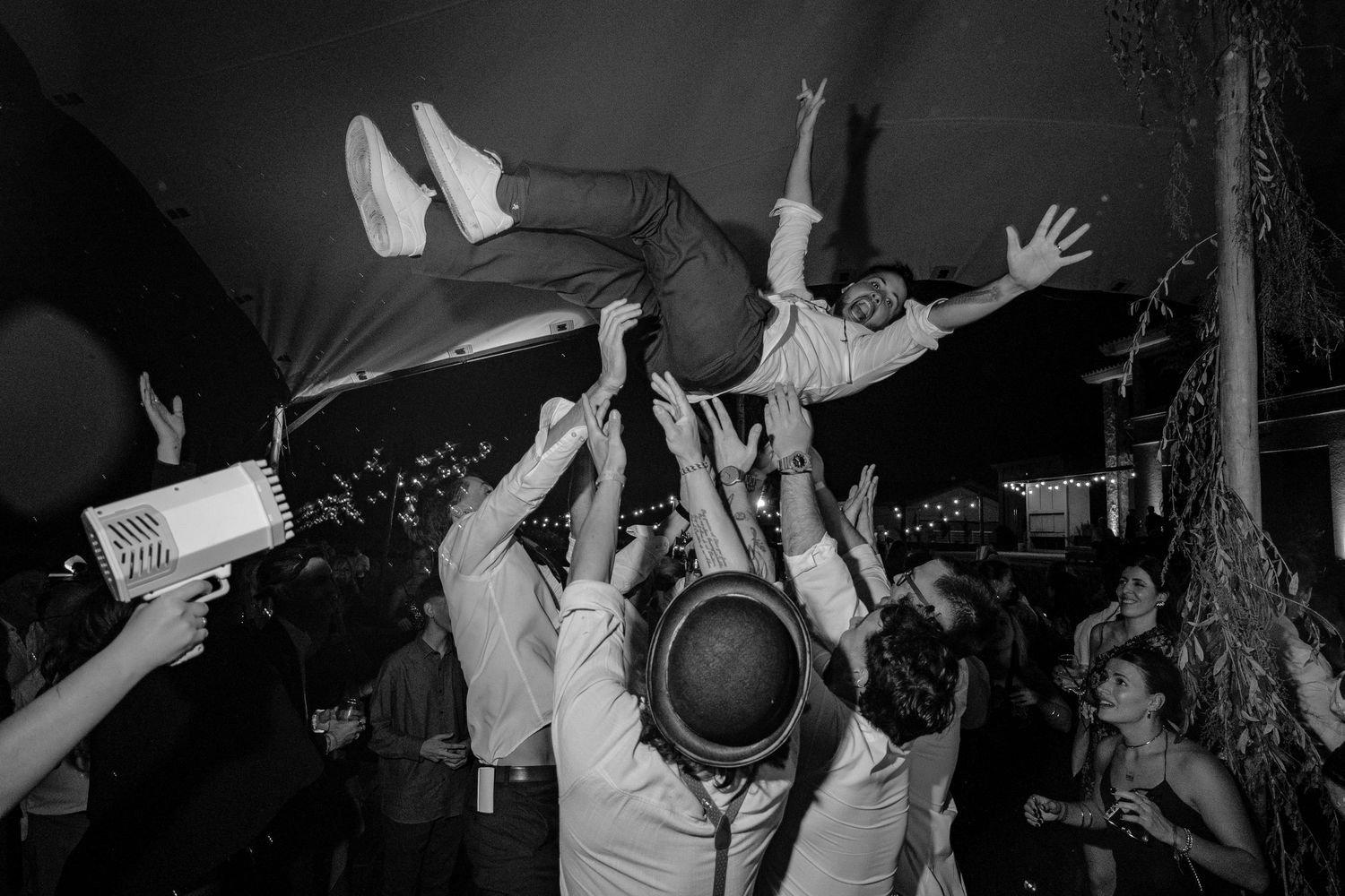 Concert performers energetically jump and dance on stage during a live music performance in black and white.