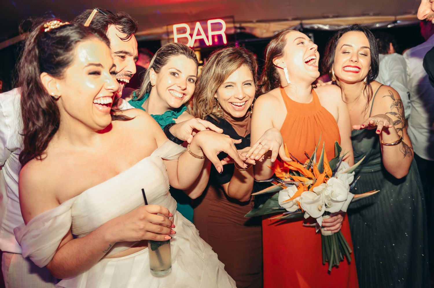 Group of friends laughing and enjoying drinks together at a lively bar with red lighting.