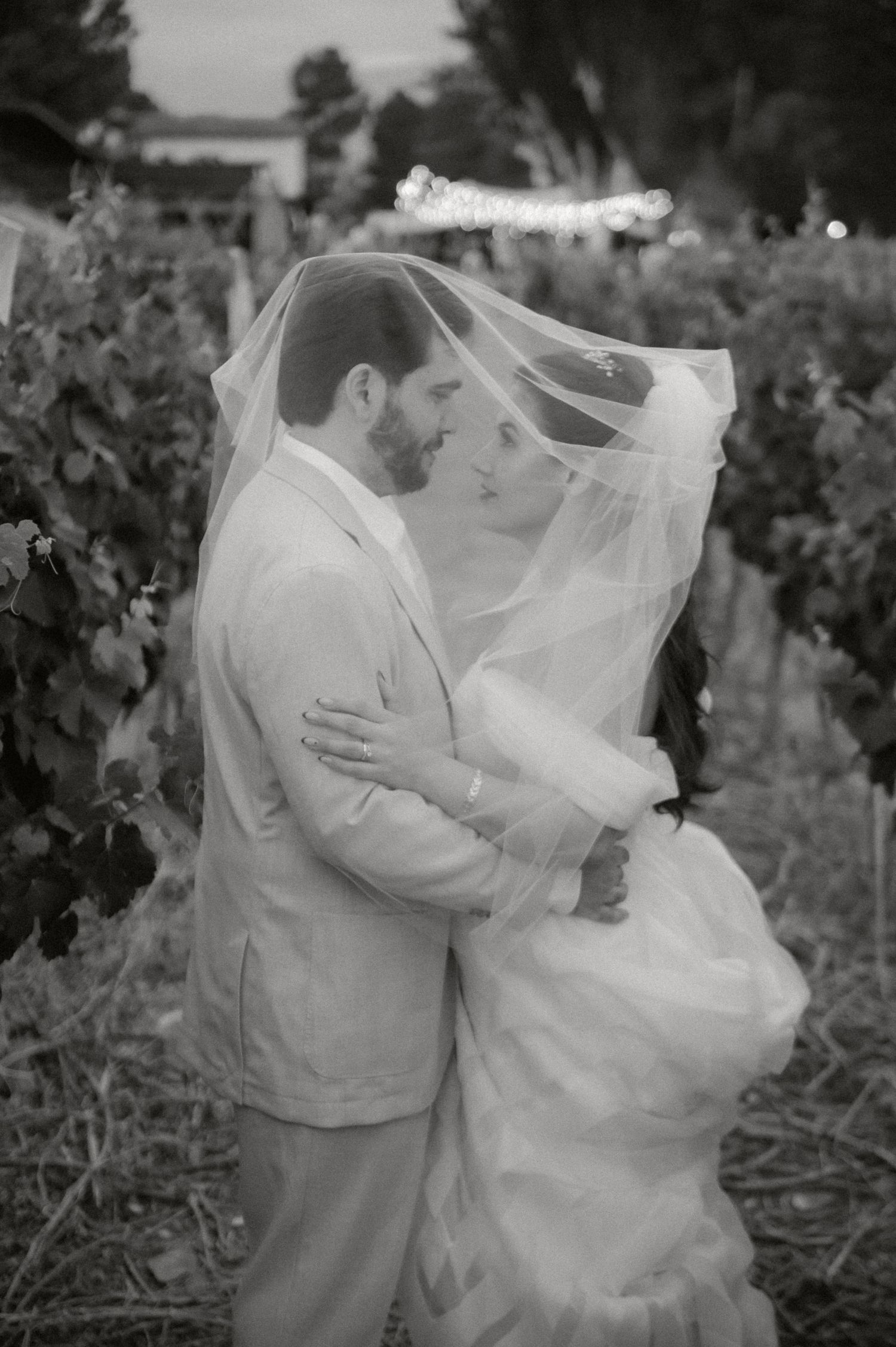 A romantic black and white wedding photoshoot sequence showing a couple embracing in a vineyard setting.