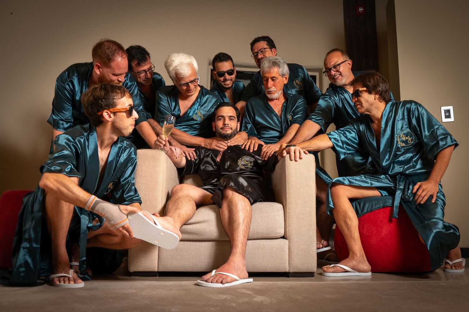 A group wearing matching blue satin shirts sits together on a couch in a casual indoor setting.