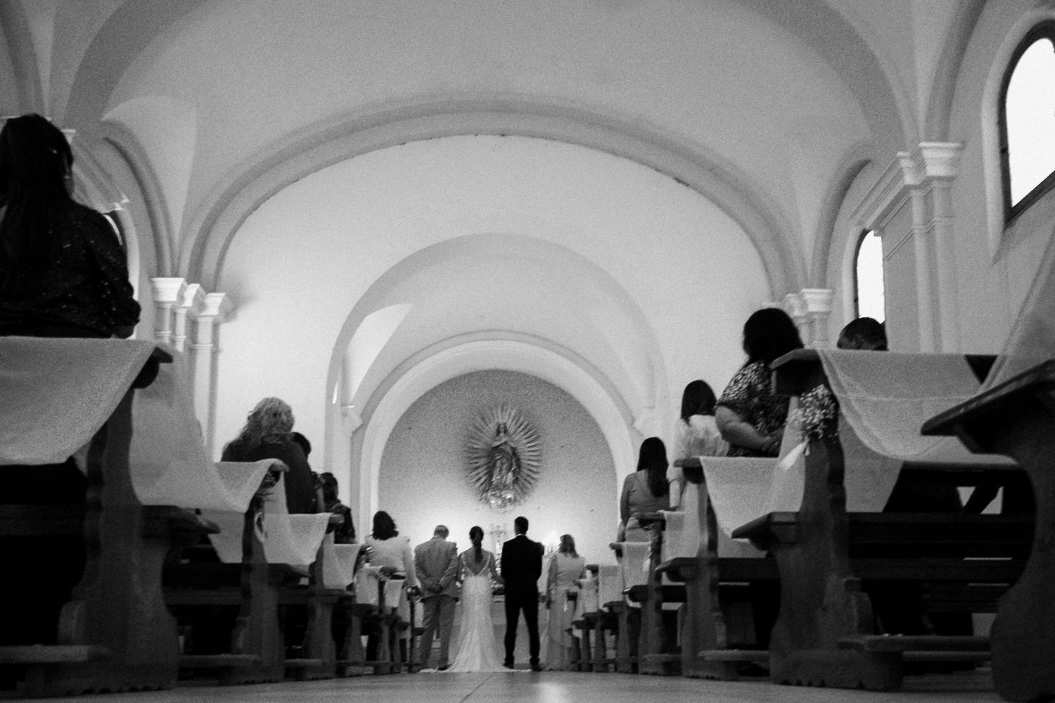A series of black and white photographs showing people in an arched gallery or museum corridor.