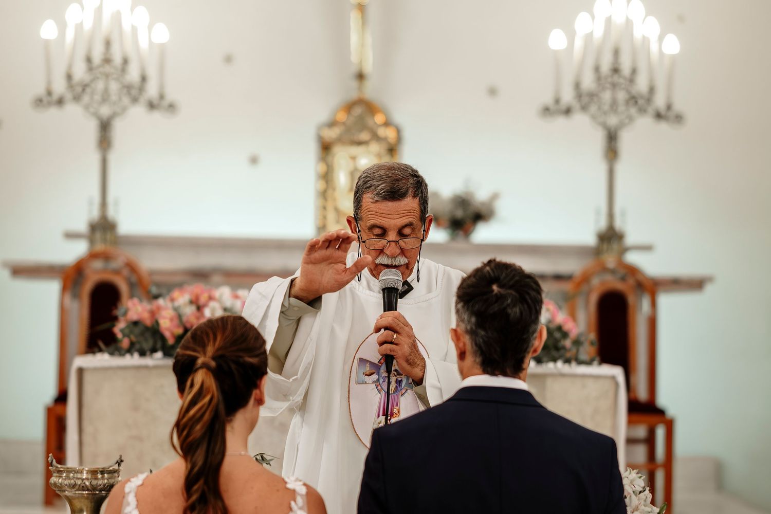 A series of candid moments during a wedding ceremony in a church with chandeliers and decorative details.