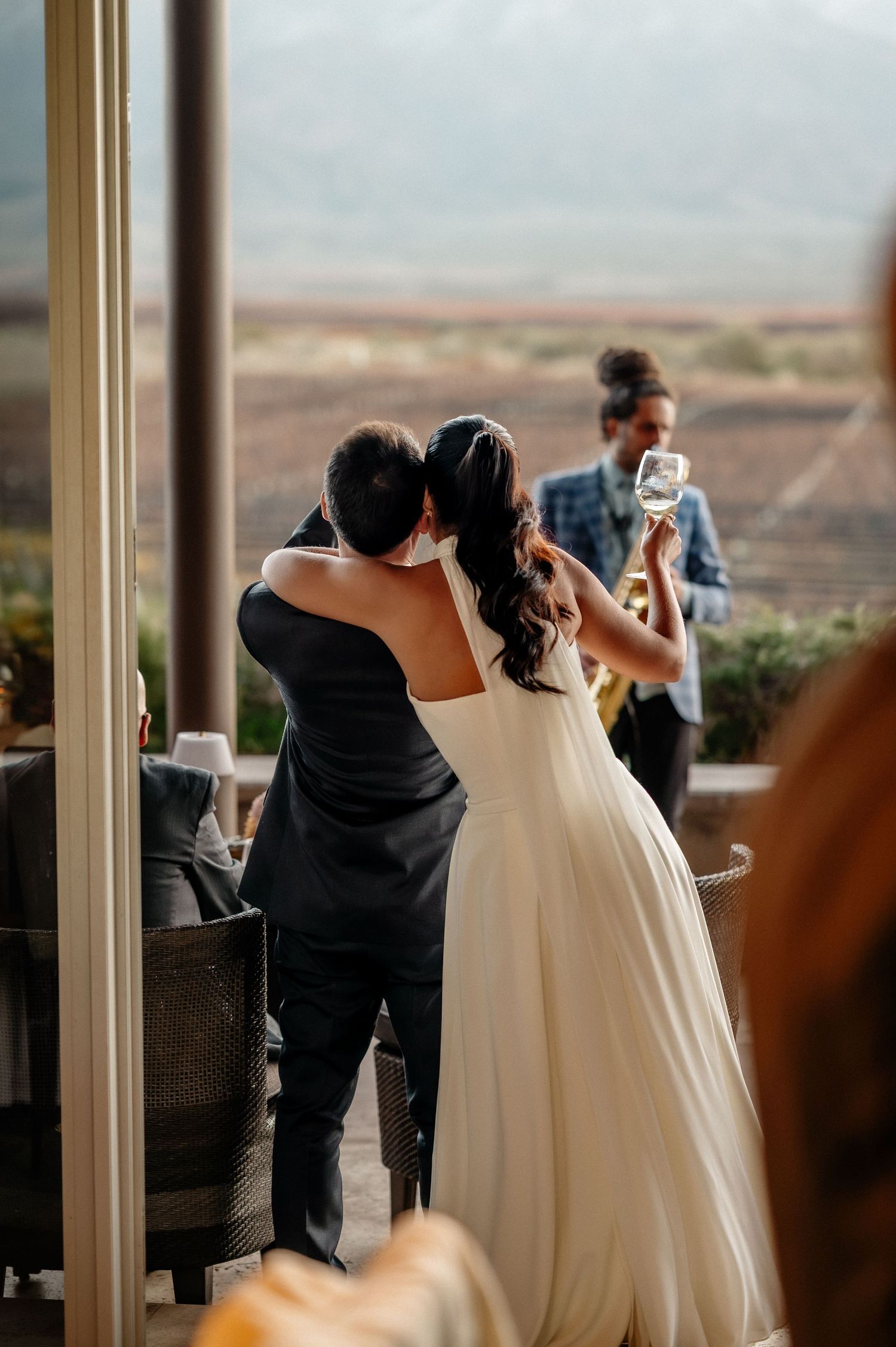 Bride and groom share a romantic embrace during their first dance at an elegant wedding reception with scenic mountain views.
