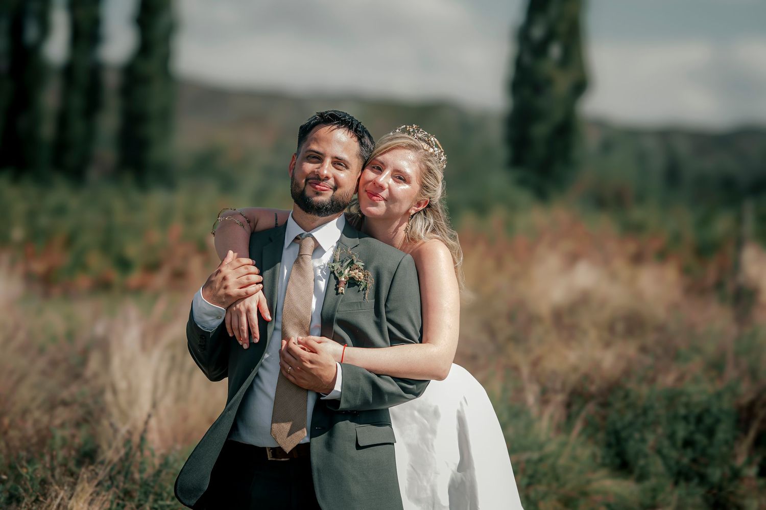 A couple shares a romantic moment dancing together outdoors in a natural setting during a wedding celebration.
