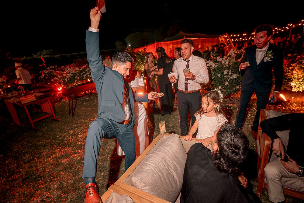 Wedding guests dance and celebrate on an outdoor dance floor illuminated by warm red lighting at night. wedding in mendoza