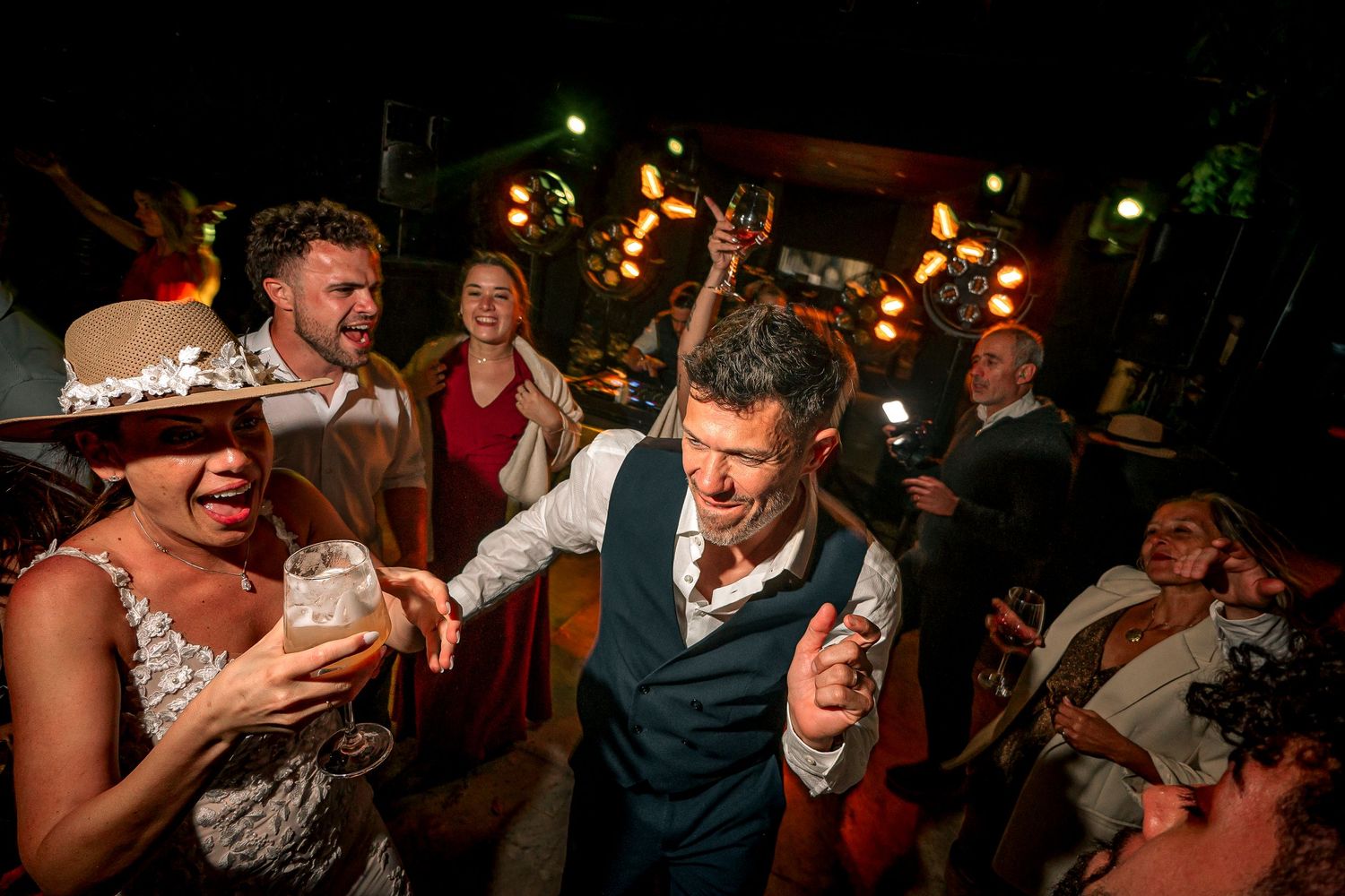People dancing and celebrating at a lively wedding reception with warm lighting and festive atmosphere.