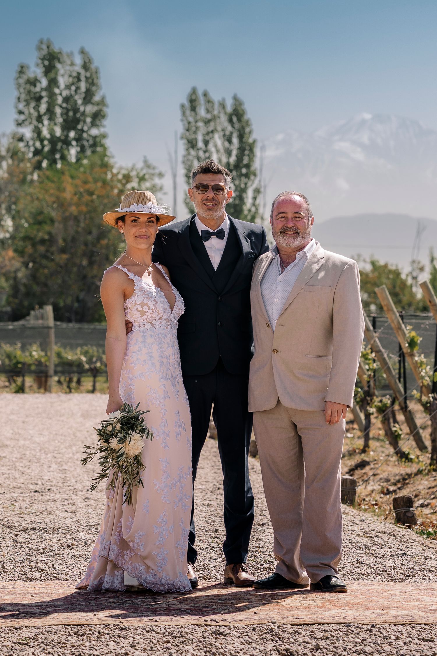 Wedding photo at a scenic vineyard with mountains in background on a sunny day.