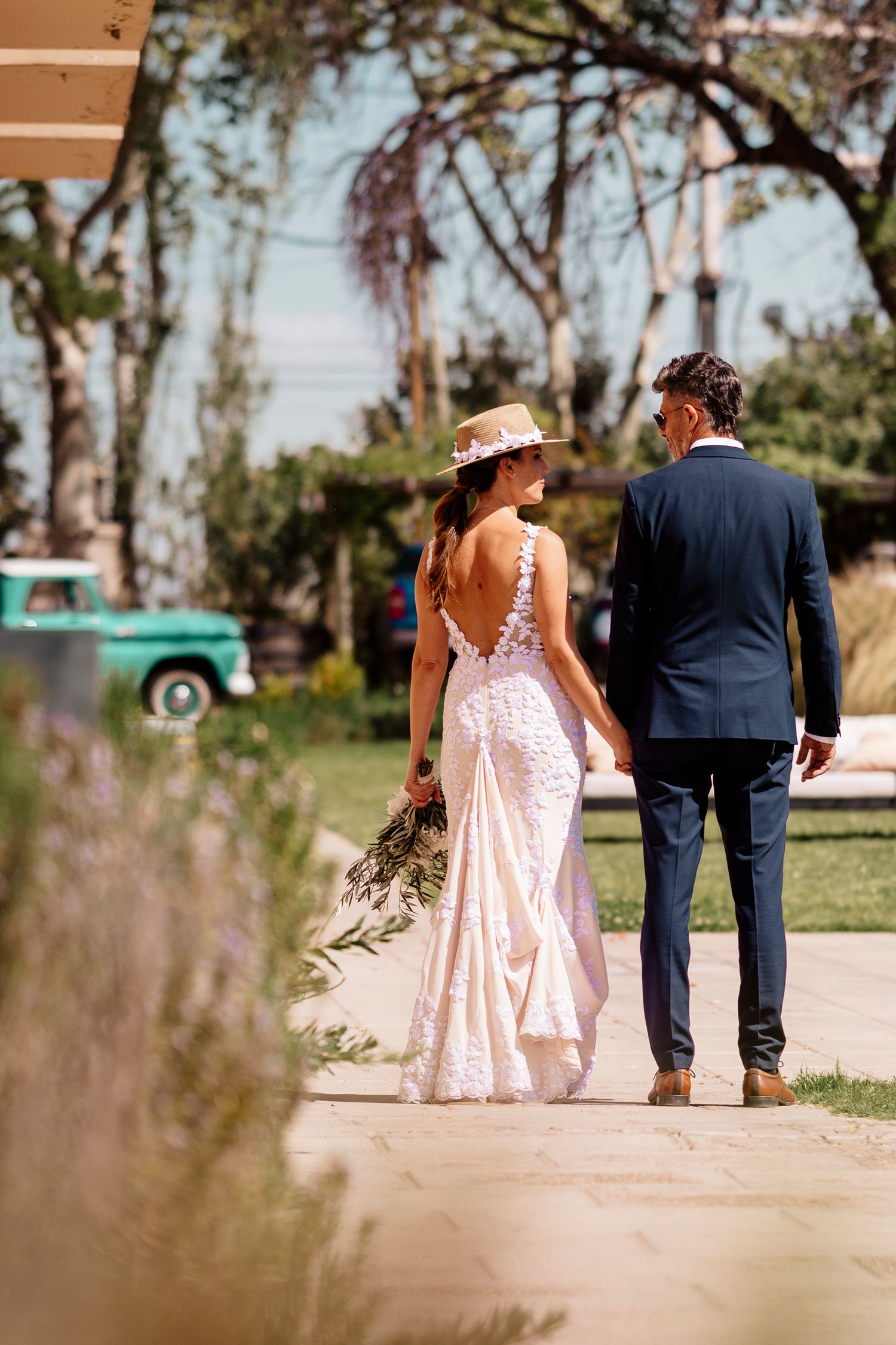 A couple in wedding attire walking together on a garden path, shown in four similar shots from behind.