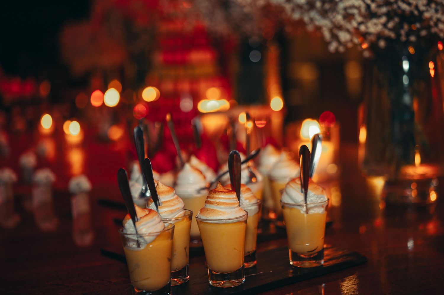 Row of glowing candles in glass holders creating a warm and atmospheric ambiance in a dimly lit setting.