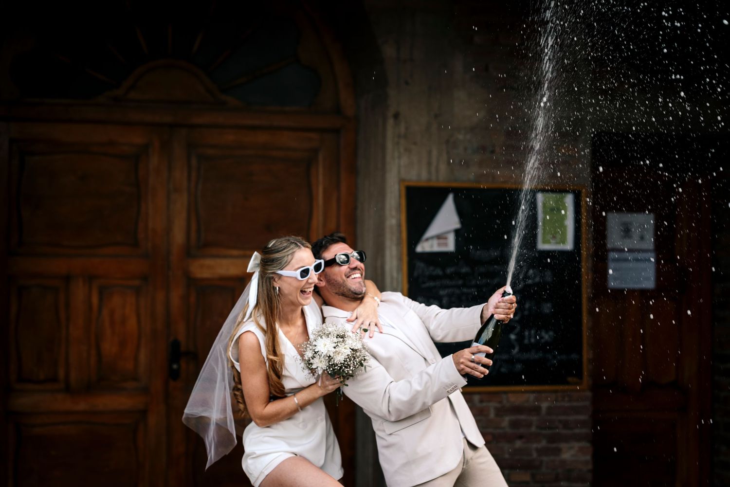 Couple celebrating in formal attire with sparkling lights in an elegant indoor setting.