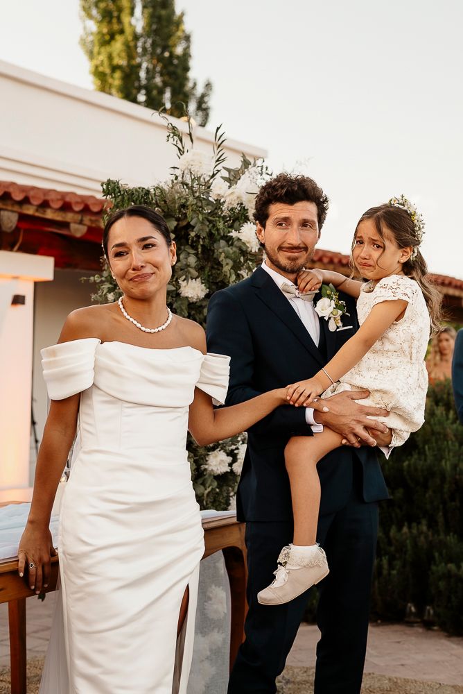 A series of candid wedding moments showing a couple in formal attire with a small child in white at an outdoor venue. wedding in mendoza