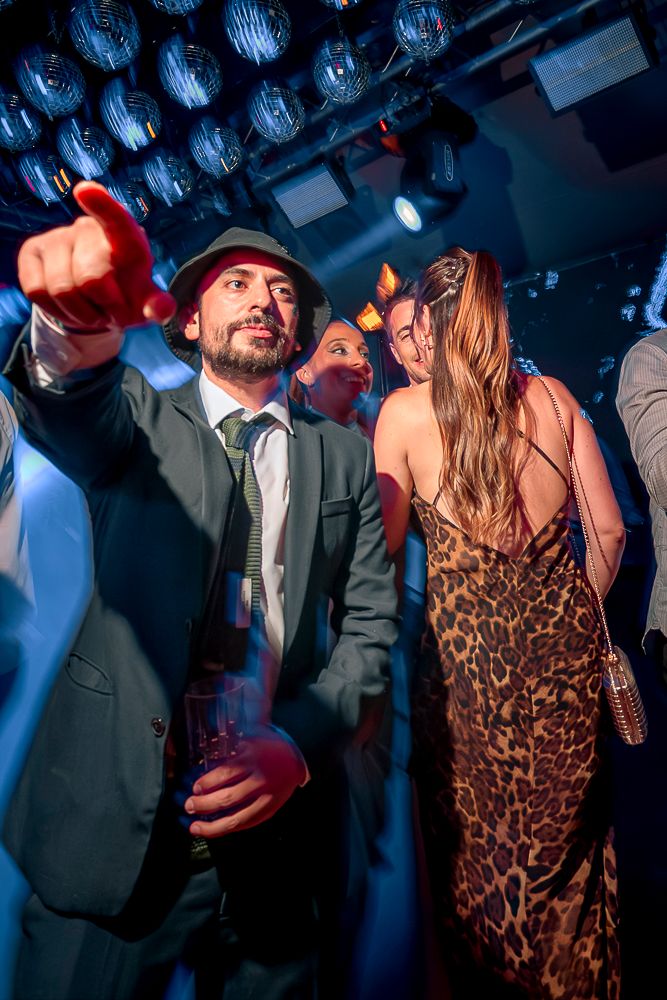 Partygoers dancing under blue lighting with a woman in leopard print dress visible in the background. wedding in mendoza