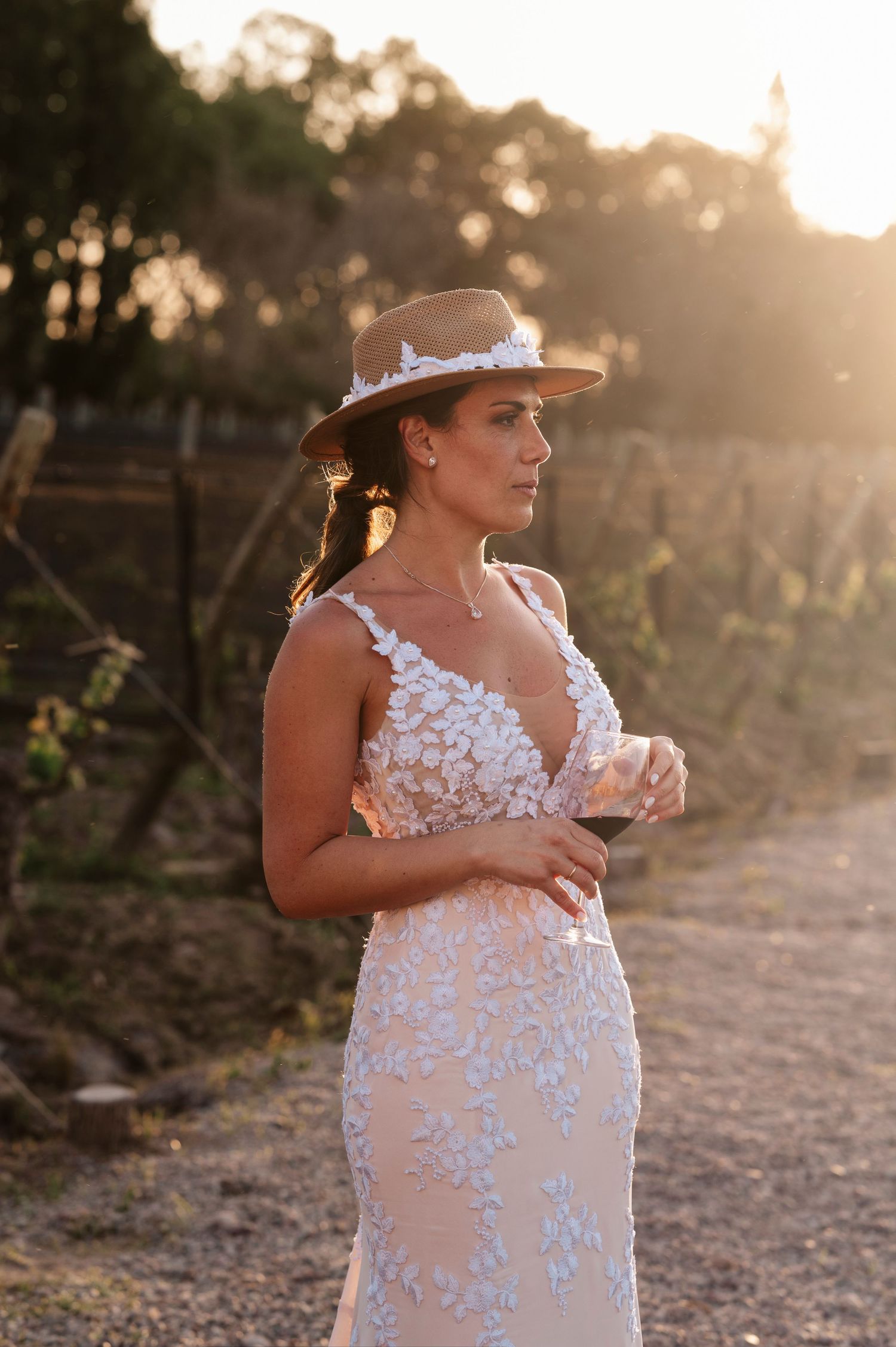 A person in a white lace wedding dress poses outdoors during golden hour sunset lighting.