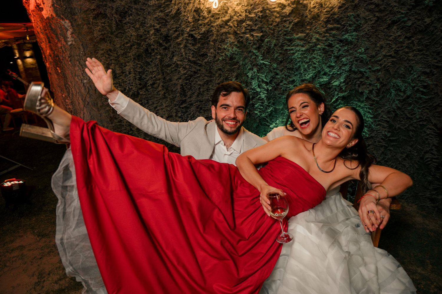 A bride in a white dress and groom in a suit dance together at their wedding reception with dramatic lighting.