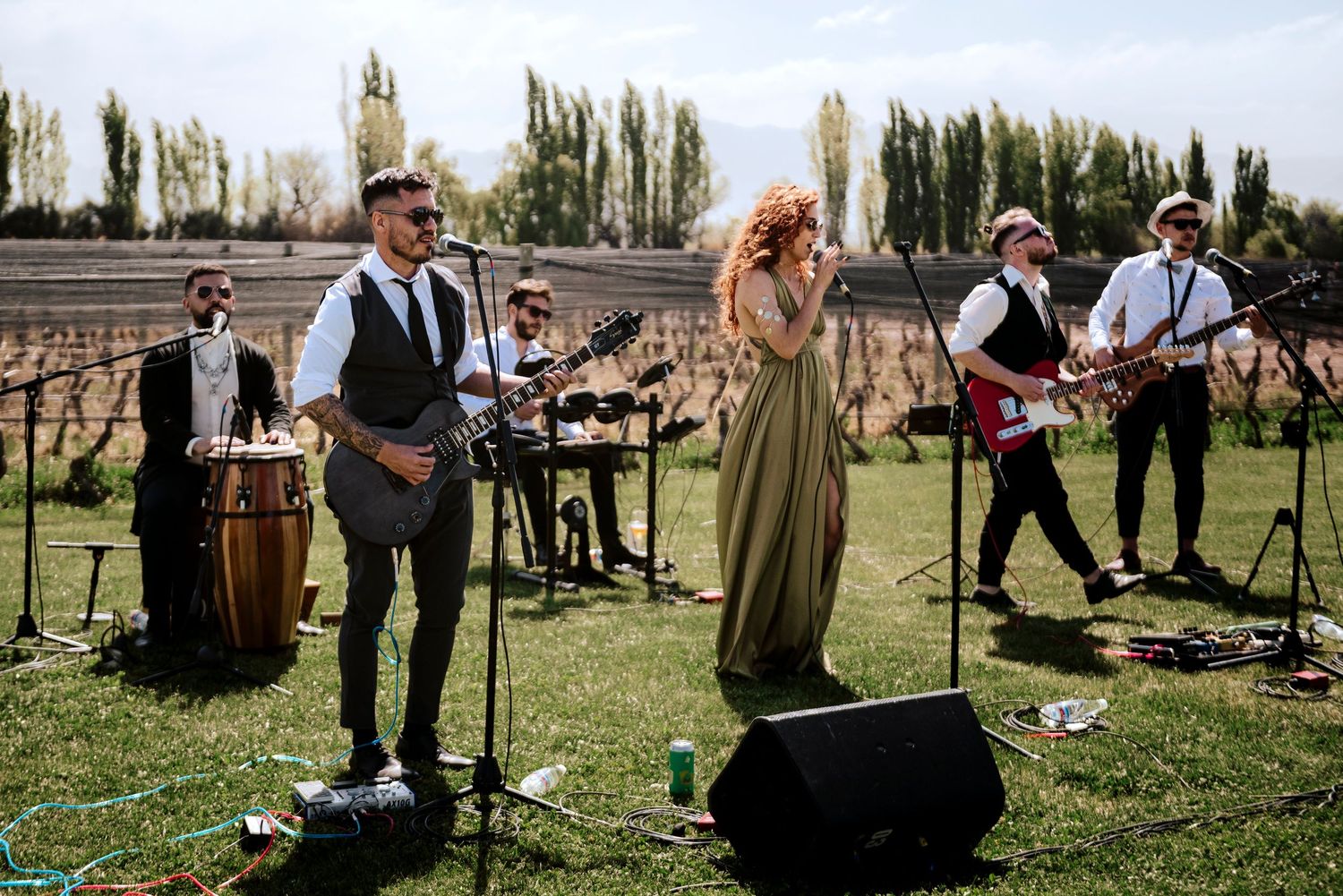 Musicians performing at an outdoor event with vintage-inspired decor and greenery.