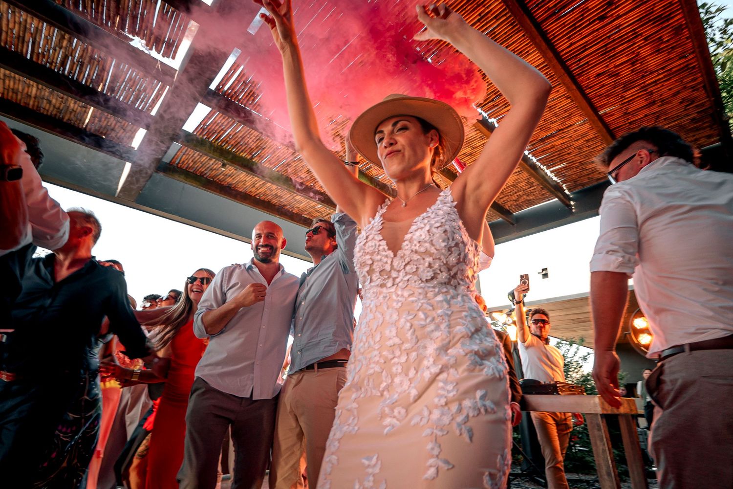 Wedding party dancing and celebrating on the dance floor under warm lighting at an indoor reception venue.